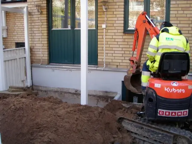Grävmaskin schaktar intill en husfasad