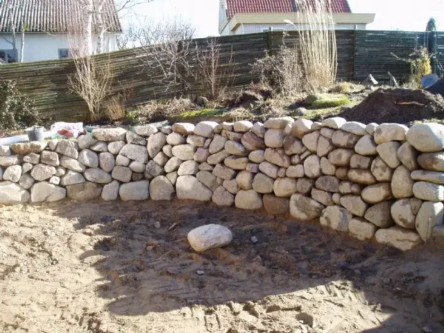Svängd mur av rundad natursten