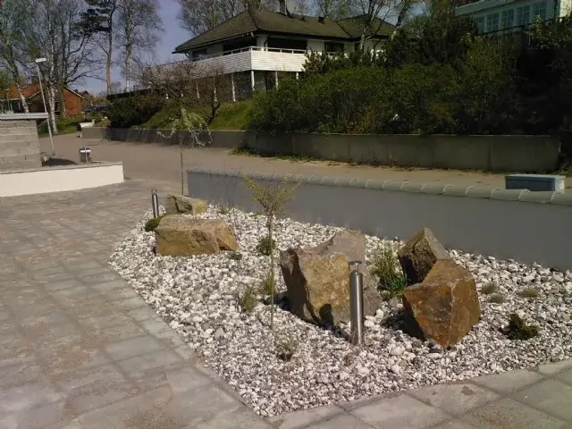 Grusbädd med stenblock och plantering framför ett hus