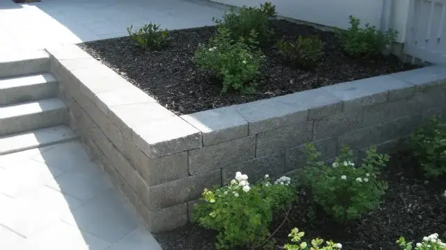 Upphöjd plantering i murblock vid en stenlagd uteplats