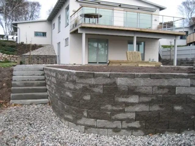 Stödmur och trappa nedanför ett nybyggt hus